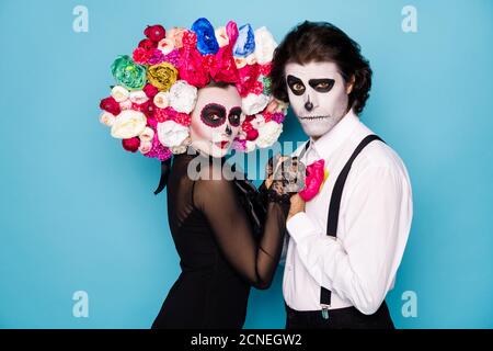 Photo de profil de couple effrayant homme fille femme mariée tenir mains danse passion tango porter robe noire tendance costume de mort décoration faciale, serre-tête roses Banque D'Images