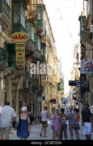 Panneaux de rue et touristes dans la rue Old Mint, la Valette, Malte Banque D'Images