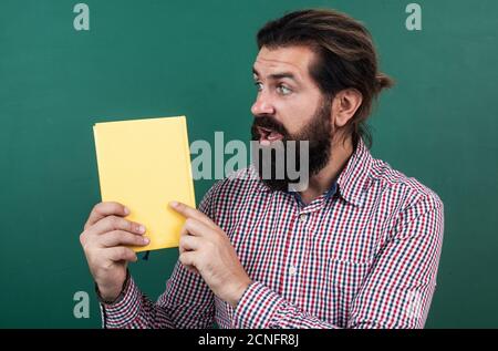 regardez cela. éducation informelle. livre de lecture d'enseignants mûrs surpris. homme barbu brutal travaille en classe avec carnet. préparez-vous à l'examen. maître de conférences à l'université. retour à l'école. Banque D'Images