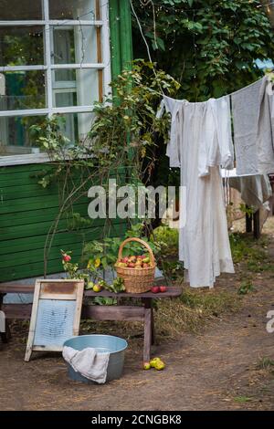 La lessive lavée sèche dans le jardin d'été, panier de pommes, planche à laver d'époque Banque D'Images