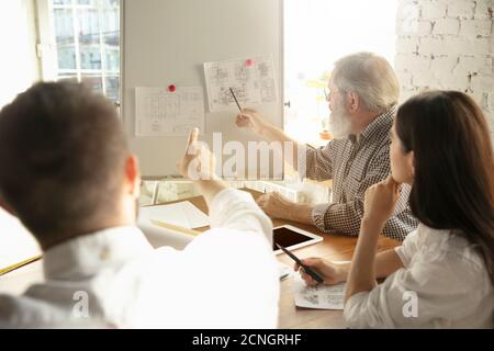 Un architecte-ingénieur de sexe masculin présente un projet de future maison pour la jeune famille. Homme travaillant au bureau avec des documents, un plan. Première maison, industriel, concept de bâtiment. Déplacement vers un nouveau lieu de vie. Banque D'Images