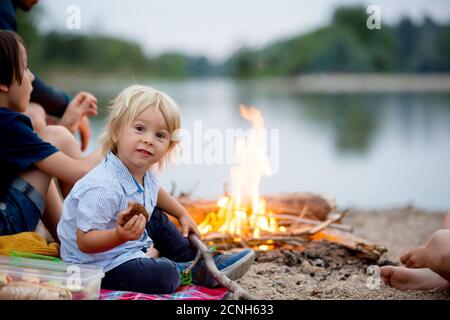 Famille ayant pique-nique et feu de camp dans la soirée près de la rivière l'été Banque D'Images