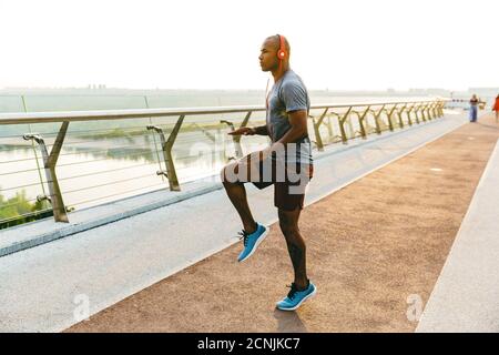 Un jeune sportif africain plein de confiance qui fait de l'exercice tout en sautant sur le pont Banque D'Images