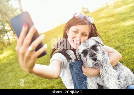 Portrait d'une heureuse femme caucasienne qui épouse son chien bien-aimé et fait selfie avec lui. Le concept de l'amour pour les animaux. Meilleur fr Banque D'Images