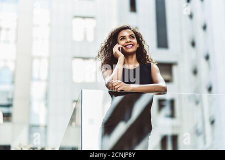 Une femme d'affaires assez mixte parle par téléphone en ville. Banque D'Images