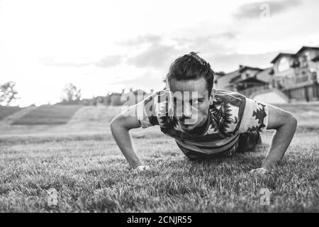 Sport. Athlète en train de pousser au coucher du soleil dans le parc. Un gars skinny s'entraînant et essayant de s'entraîner. Entraînement dur Banque D'Images