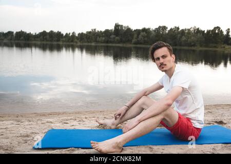 Un jeune homme se détende sur la plage semble juste avec le ciel du soir. Conceptuel pour la pensée et la recherche de se concentrer quelque chose Banque D'Images