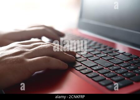 Vue latérale des mains de l'homme qui travaillent sur son ordinateur portable assis à une table en bois. Concept de travail et d'étude Banque D'Images