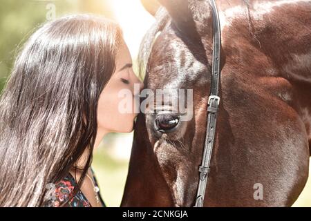 Cheval et fille partagent un moment émotionnel en gros plan comme ils semblent baiser. Face à face. Amour animaux concept. Amour cheval Banque D'Images