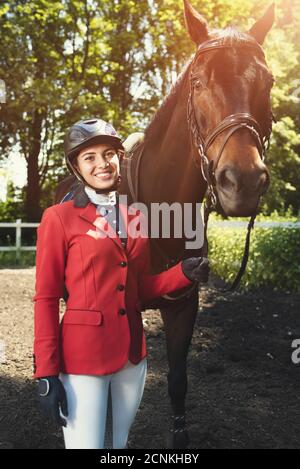 Souriant Girl rider et un cheval posant dans la forêt de printemps. Regardant dans la caméra Banque D'Images