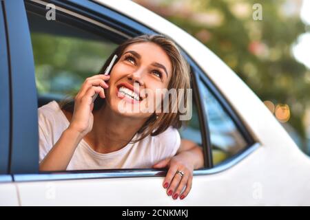 Belle femme avec téléphone en voiture, jour ensoleillé Banque D'Images