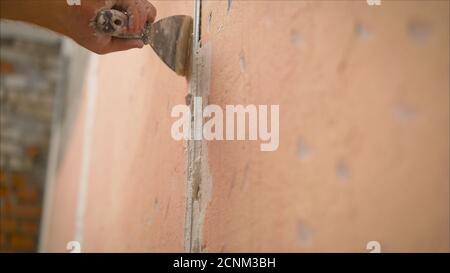 Ouvrier de construction avec longue truelle plâtrage d'un mur. Murs de mastic Banque D'Images