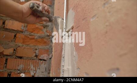 Revêtement décoratif en plâtre. L'homme fait une texture déchiquetée sur le mur à l'aide d'une spatule. Application de plâtre sur le mur Banque D'Images