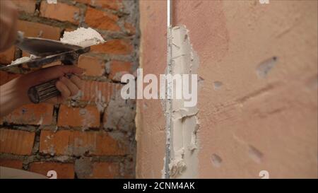 Revêtement décoratif en plâtre. L'homme fait une texture déchiquetée sur le mur à l'aide d'une spatule. Application de plâtre sur le mur Banque D'Images