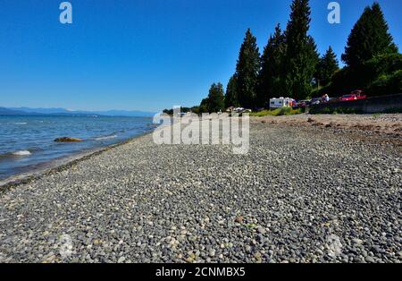 Les gens qui profitent d'une belle journée de printemps se détendent et jouent dans l'eau à Qualicum Beach, sur l'île de Vancouver Colombie-Britannique Canada. Banque D'Images