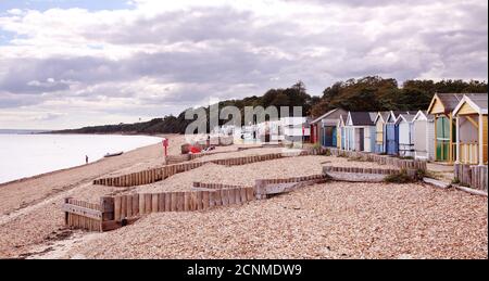 Plage de galets de CalShot sur les eaux de Solent et Southampton, sur la côte du Hampshire. Groynes en bois et cabines de plage. Banque D'Images