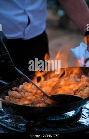 Gros plan d'un homme cuisant des crevettes flambeées, France