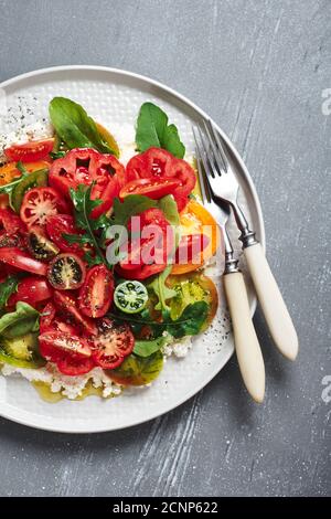 Salade avec tomates rouges, jaunes, vertes, arugula et ricotta. Banque D'Images