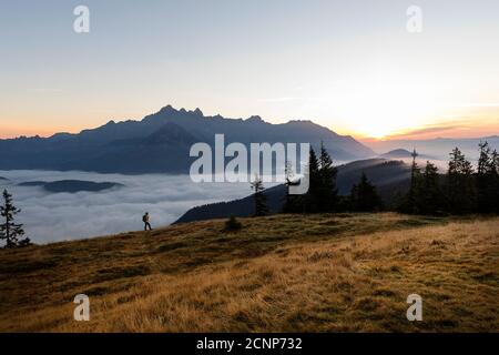 Femme debout sur une montagne couverte d'herbe regardant le lever du soleil, Rossbrand, Radstadt, Autriche Banque D'Images