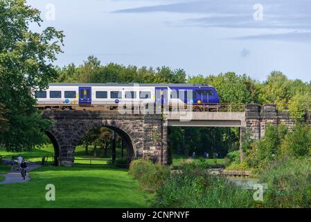 Un train diesel Northern Rail traverse le viaduc de la vallée de Sankey au-dessus du canal disused dans le parc Linaer à l'ouest de Warrington. Banque D'Images