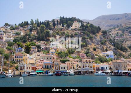 Vue sur la magnifique baie avec des maisons colorées sur la colline de l'île de Symi, Grèce Banque D'Images