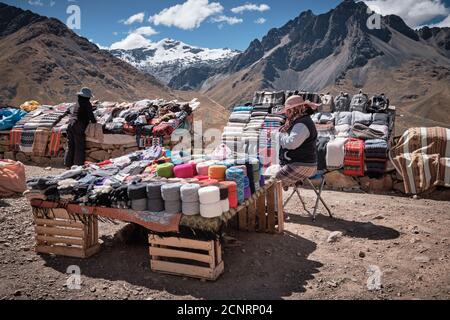 Un marché en bord de route dans les hautes Andes de l'Altiplano, Pérou, vendant des textiles et des tissus, des vêtements et des souvenirs touristiques Banque D'Images