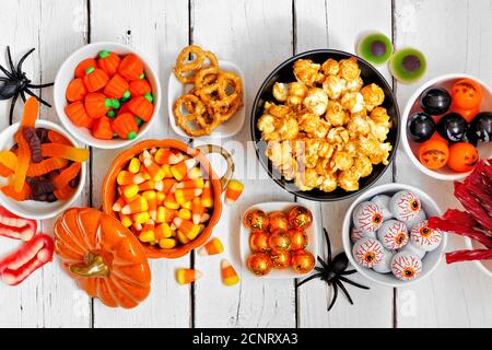 Table de buffet Halloween sur fond de bois blanc. Assortiment de gâteries amusantes et effrayantes. Vue de dessus. Banque D'Images