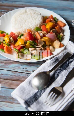 Le riz ainsi que le poulet et les légumes saute dans un blanc plaque Banque D'Images