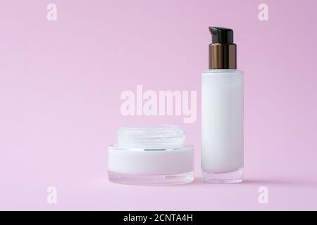Crème blanche pour le visage dans un pot et lotion hydratante dans un flacon en verre sur fond de papier rose. Concept cosmétique naturel. Soins et protection de la peau en de Banque D'Images