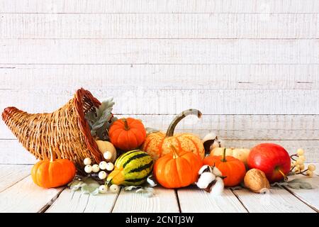 Cornucopia de Thanksgiving remplie de légumes d'automne et de citrouilles contre A. arrière-plan rustique en bois blanc Banque D'Images