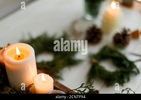 Bougies allumées sur fond rustique avec couronne de noël, cônes de pin et ornements sur table en bois le soir. L'arrivée de l'atelier de vacances, ambiance chaleureuse Banque D'Images