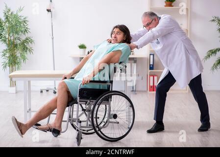 Jeune patient en chaise roulante et médecin traumatologue expérimenté Banque D'Images