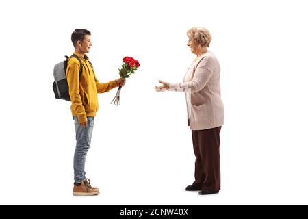 Photo de profil d'un adolescent de sexe masculin donnant un bouquet de roses rouges à une femme âgée isolée sur arrière-plan blanc Banque D'Images