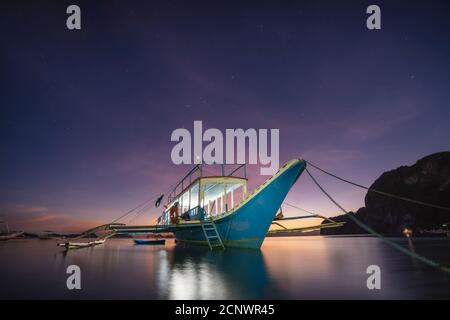 Bateau Banca à la plage de Corong illuminé au crépuscule éclairé par la dernière lumière du coucher du soleil, El Nido, Palawan, Philippines. Banque D'Images