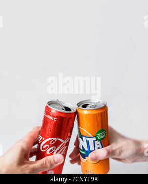 Minsk, Bélarus - 18 septembre 2020 : deux mains font du clin d'œil avec des canettes Coca-Cola et Fanta. Deux boissons produites par Coca-Cola Company Banque D'Images