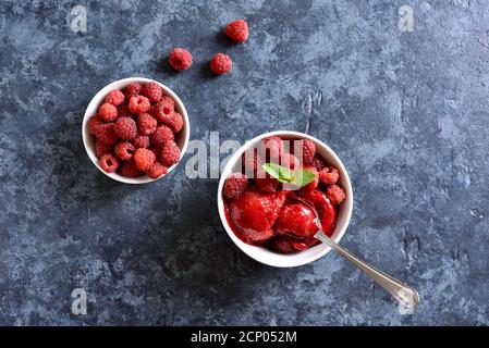 Sorbet framboise, cuillère à crème glacée avec baies fraîches dans un bol sur fond de pierre bleue avec espace de texte libre. Délicieux dessert froid d'été. Vue de dessus, Fla Banque D'Images