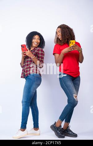 les jeunes femmes africaines utilisent leur téléphone, se regardant les unes les autres souriantes Banque D'Images