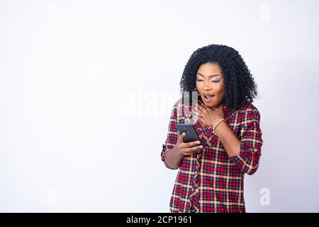 une jeune femme qui tient son téléphone a l'air choquée et inquiète Banque D'Images