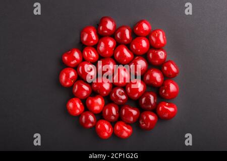 Cerises sur fond noir, vue de dessus, plat, gros plan. Banque D'Images