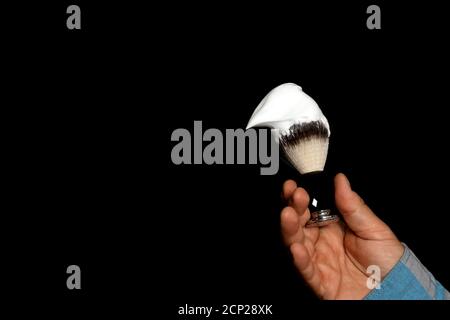 homme tenant la brosse et la mousse dans les mains pour se raser arrière-plan noir Banque D'Images