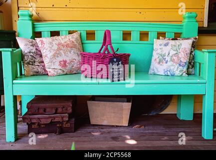 Un banc de bois peint empilé avec des coussins et un panier avec porte-documents et une boîte en dessous avec un joli manuscrit signez tous les vieux Banque D'Images