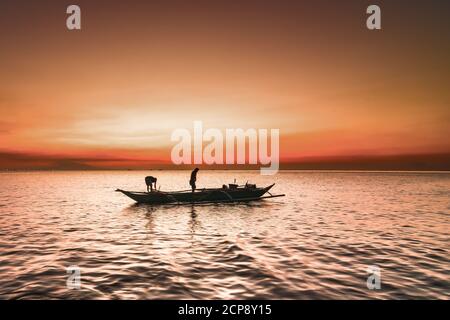 Pêcheurs sur un bateau au coucher du soleil, baie de Manille, Manille, Philippines Banque D'Images