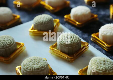 Les gâteaux de lune en peau de neige au milieu du processus d'emballage. Placé sur un récipient en plastique doré ; prêt à être fermé et scellé Banque D'Images