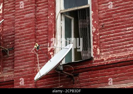 Plat satellite sur le mur d'une ancienne maison en brique Banque D'Images