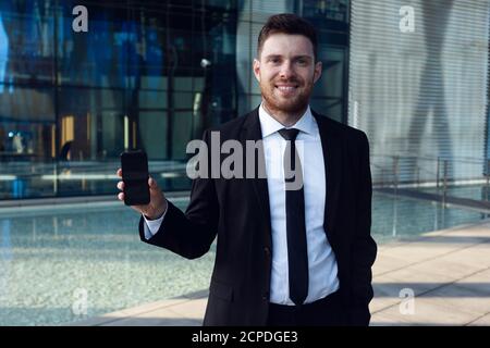 Homme d'affaires montrant le téléphone. Homme d'affaires freelance portant un costume Banque D'Images