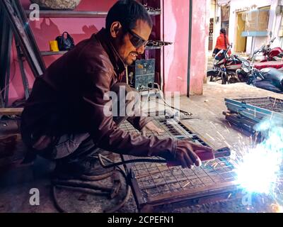 DISTRICT KATNI, INDE - 08 JANVIER 2020 : un forgeron indien soudant sur une structure en acier. Banque D'Images