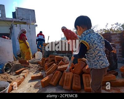 DISTRICT KATNI, INDE - 13 JANVIER 2020 : un petit garçon indien qui lance un balai pendant les travaux de construction de murs. Banque D'Images