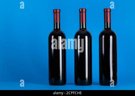 Trois bouteilles de vin sur fond bleu. Espace pour le texte. Vue de dessus. Banque D'Images