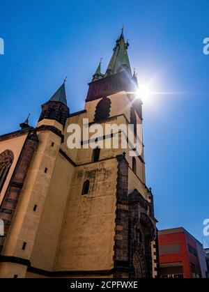 Tour penchée de l'église avec le soleil jetant des rayons sur son sommet. Église de l'Assomption de la Vierge Marie - Usti nad Labem / République tchèque Banque D'Images