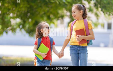 Élèves de l'école primaire. Filles avec sacs à dos à l'extérieur. Début des leçons. Premier jour de l'automne. Banque D'Images